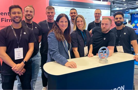 Three Karbon team members viewing a computer monitor in an office.